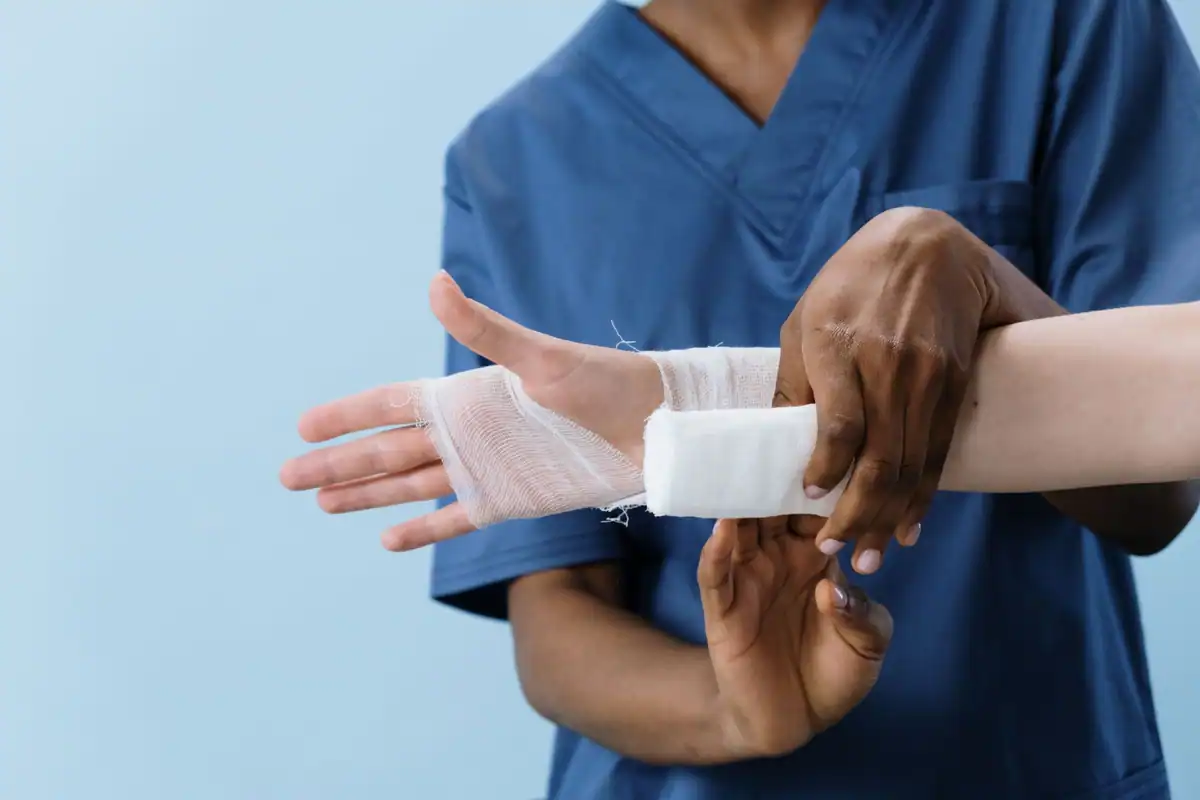 Cadru medical care bandajează mâna rănită a unui salariat după un accident