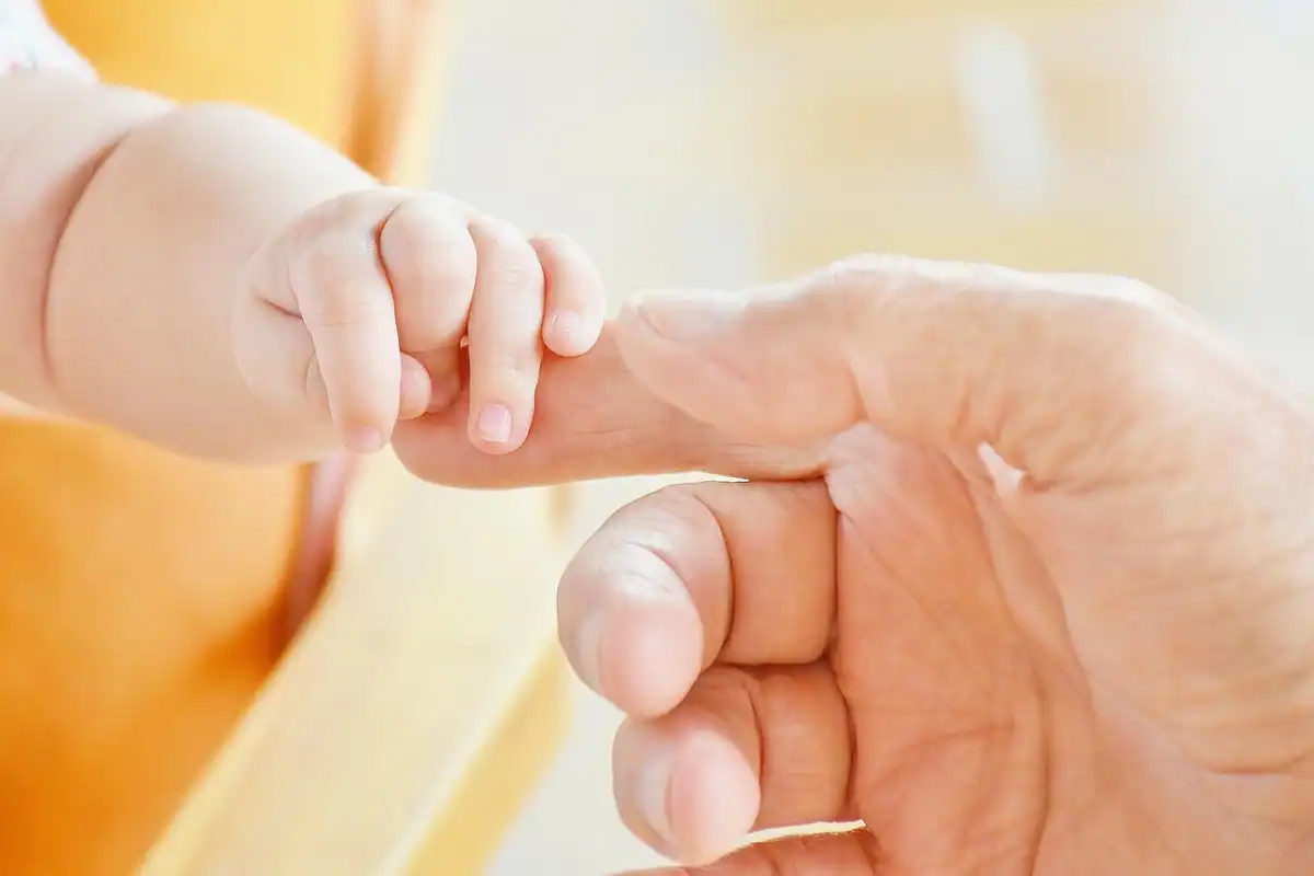 Mână de nou-născut care strânge degetul unui părinte