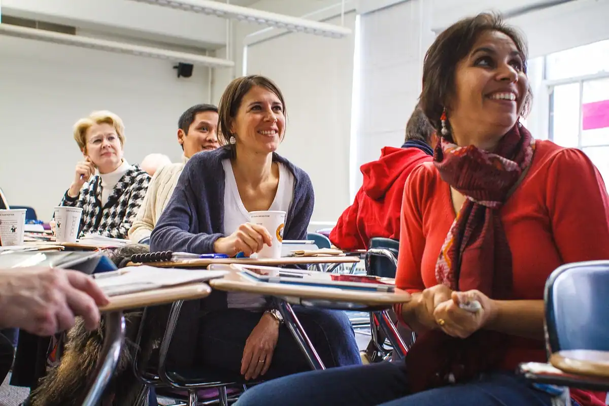 Cursanți adulți zâmbitori la un curs de pregătire, în sala de clasă