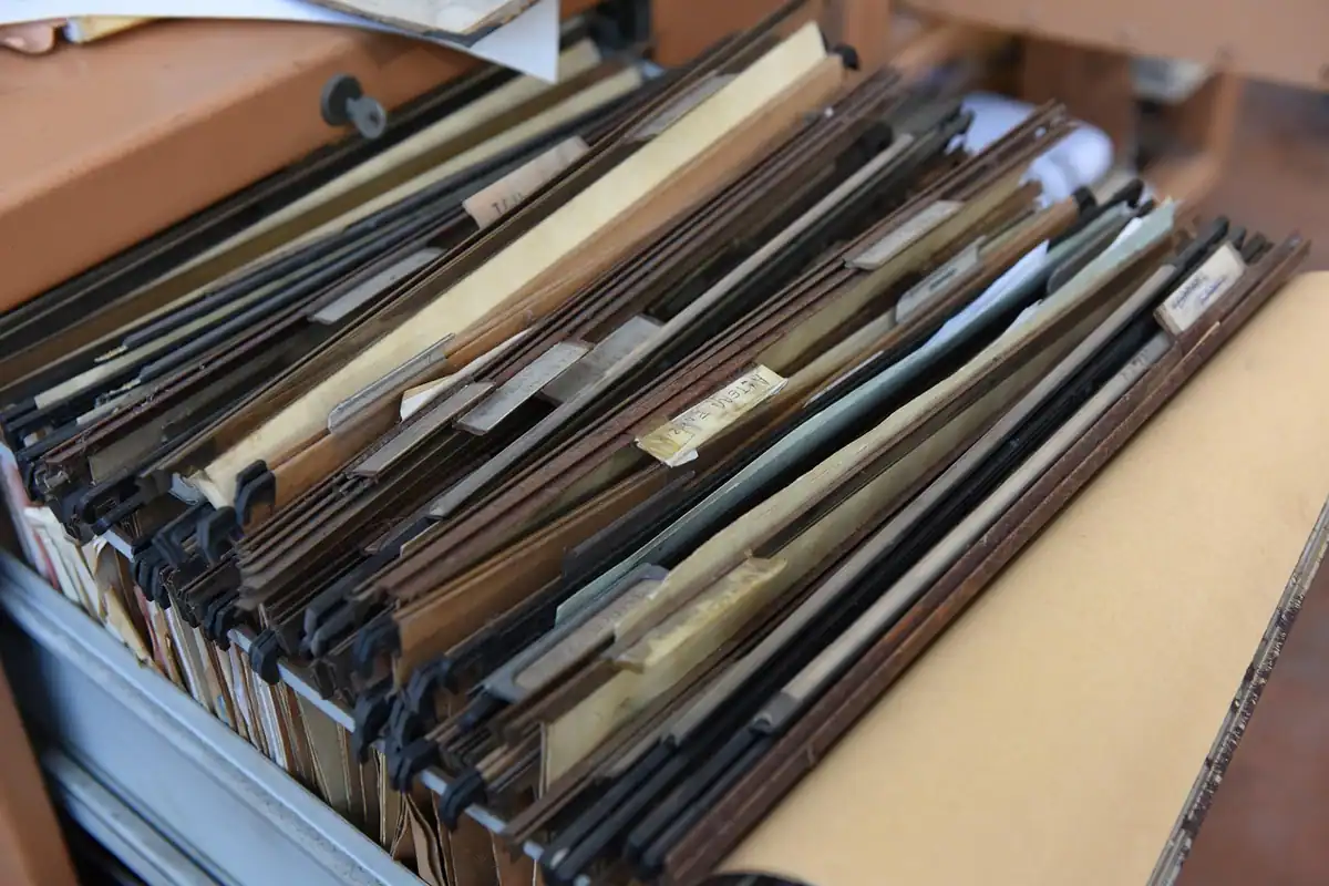 Dosare vechi așezate în sertar, cu documentele salariatului care pleacă