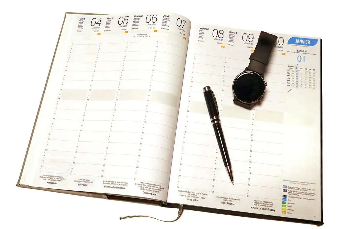 Agendă deschisă cu calendar și un pix, pentru notarea programului de lucru zilnic
