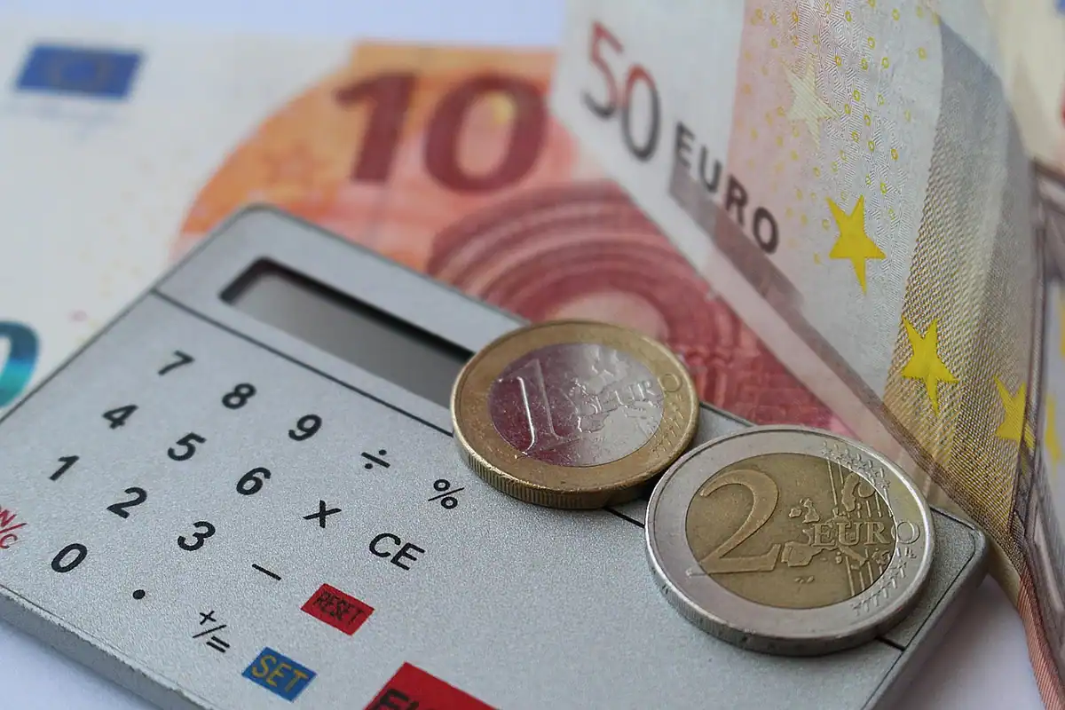 Bancnote și monede lângă un calculator, pentru banii primiți la lichidarea de la plecarea din firmă