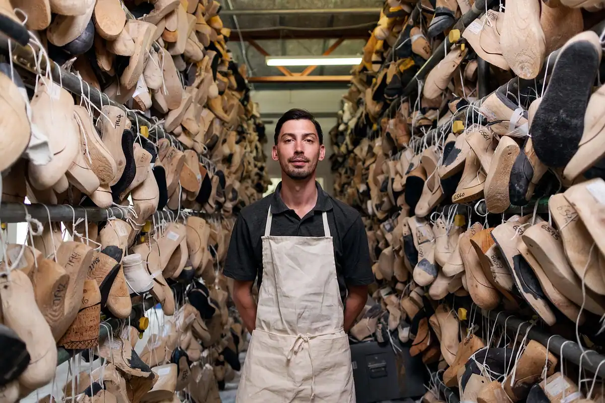 Muncitor într-un atelier de fabrică, lângă rafturi cu produse, la un loc de muncă temporar