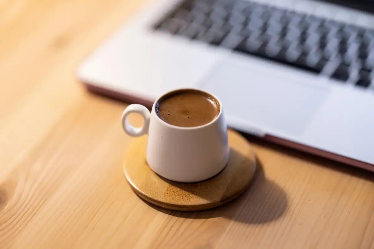 Ceașcă de cafea lângă un laptop, în timpul pauzei de masă