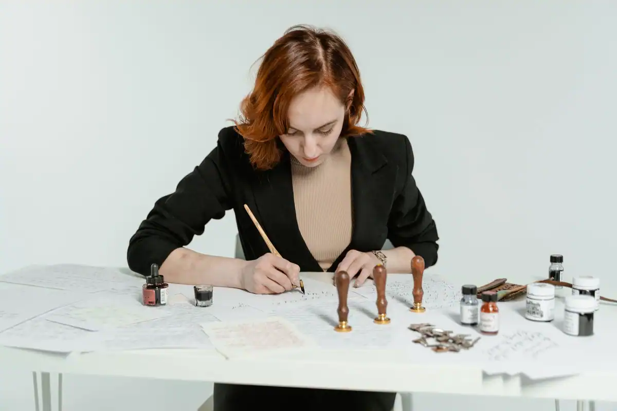 Femeie care scrie atent la birou, printre ștampile, cerneală și hârtii