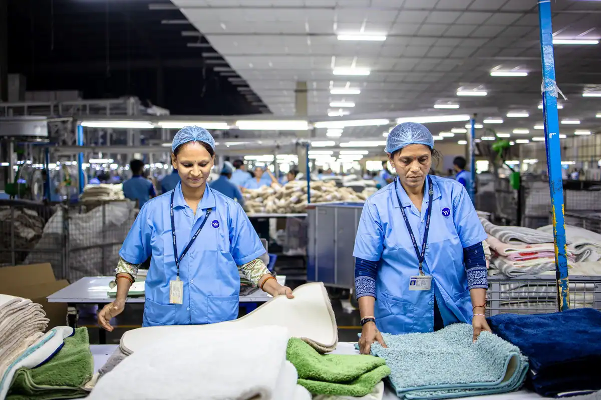 Două muncitoare în halate albastre, într-o fabrică de textile, cu program în ture