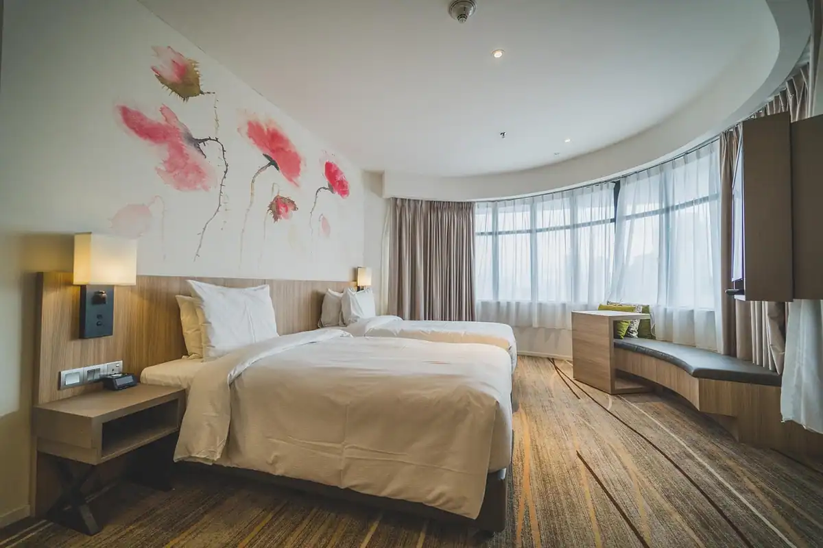 Cameră de hotel luminoasă cu pat dublu și decor modern, pregătită pentru un sejur de concediu