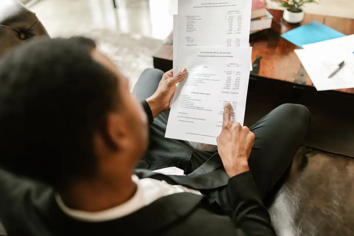 Bărbat care verifică atent un document cu sume, stând pe canapea