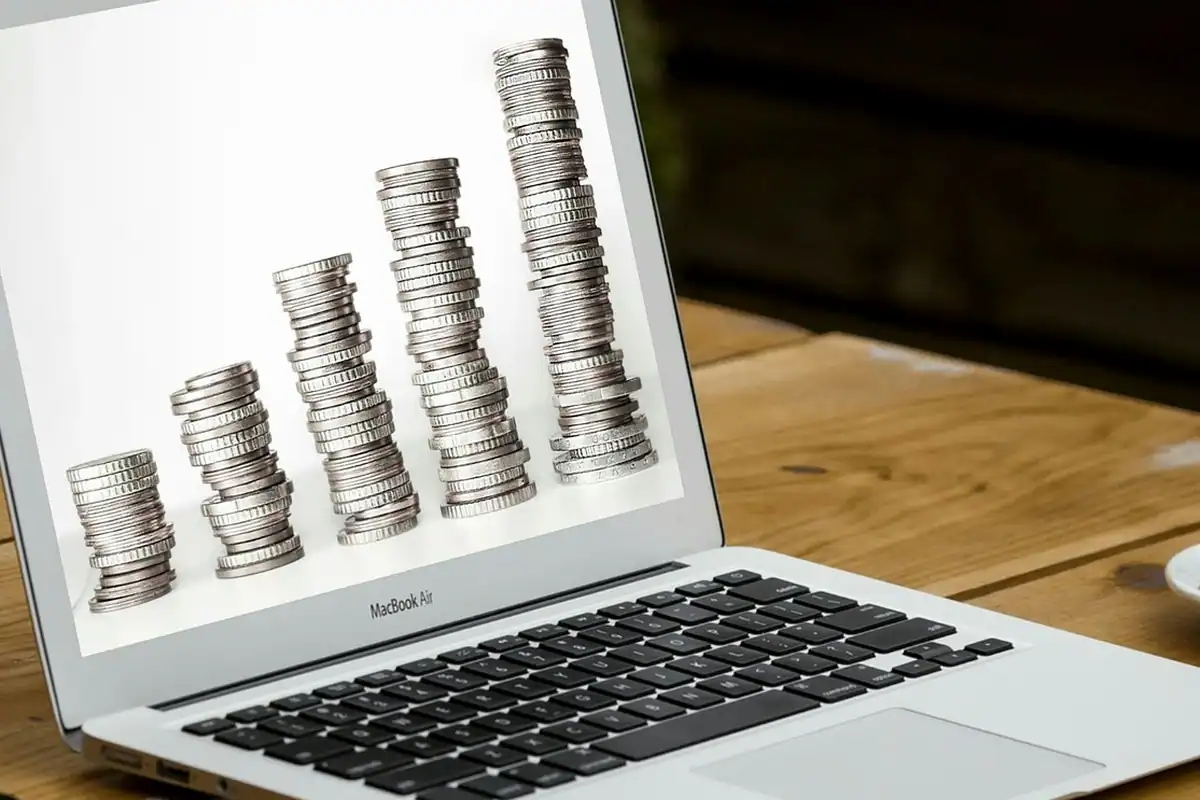 Laptop cu monede de euro așezate pe tastatură, pentru calculul veniturilor brute și nete