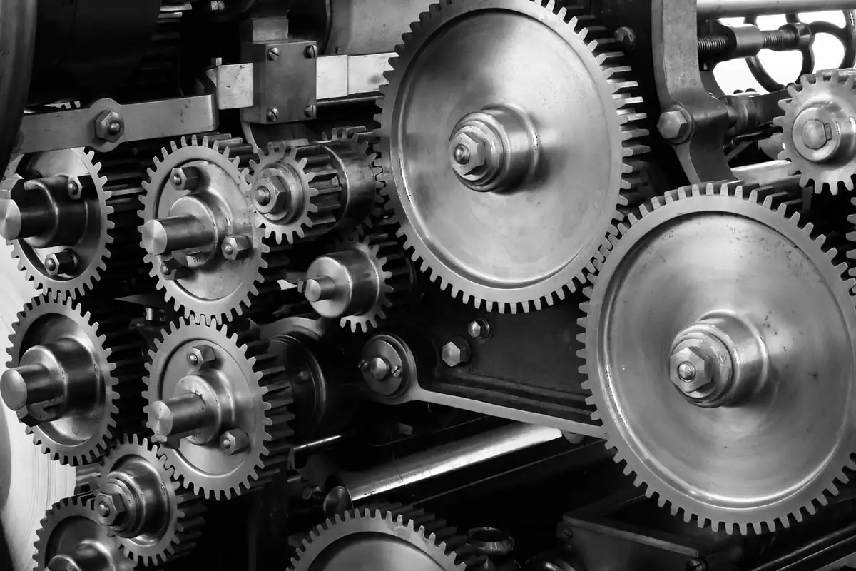 Roți dințate metalice în alb și negru ale unui utilaj industrial oprit în șomaj tehnic