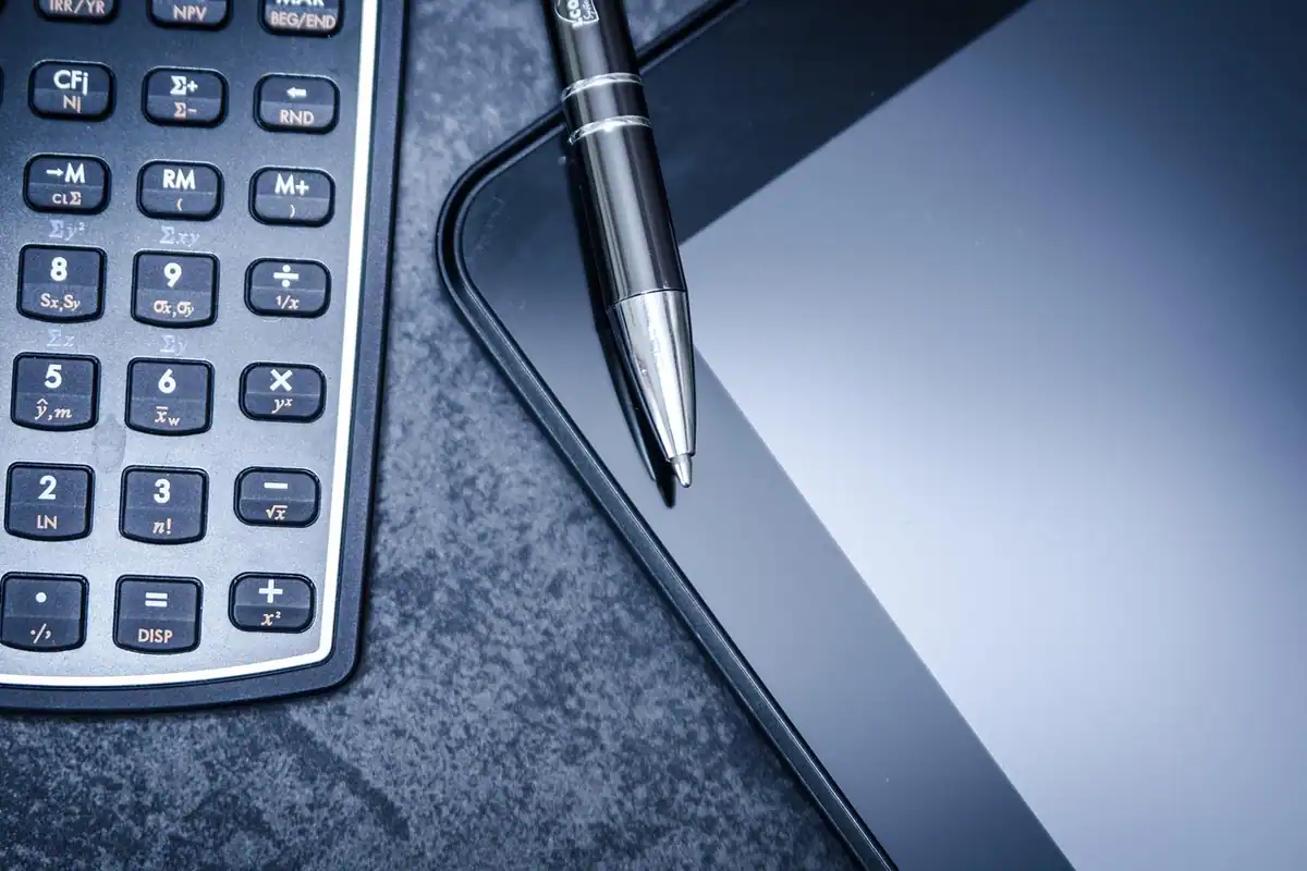 Mână care folosește un calculator pe un birou, pentru calcule exacte