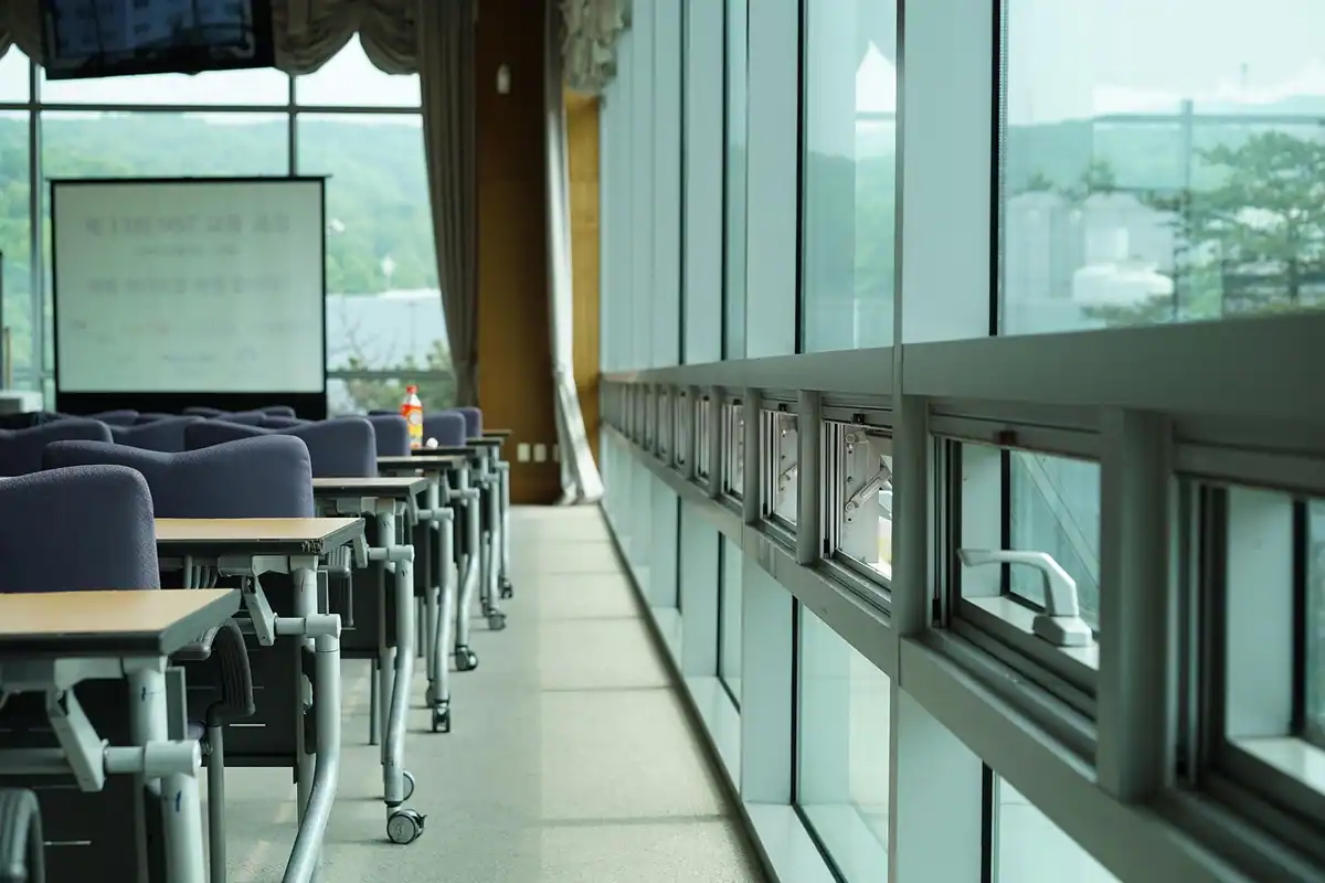 Amfiteatru luminos cu ferestre mari și locuri goale, folosit pentru seminare și conferințe