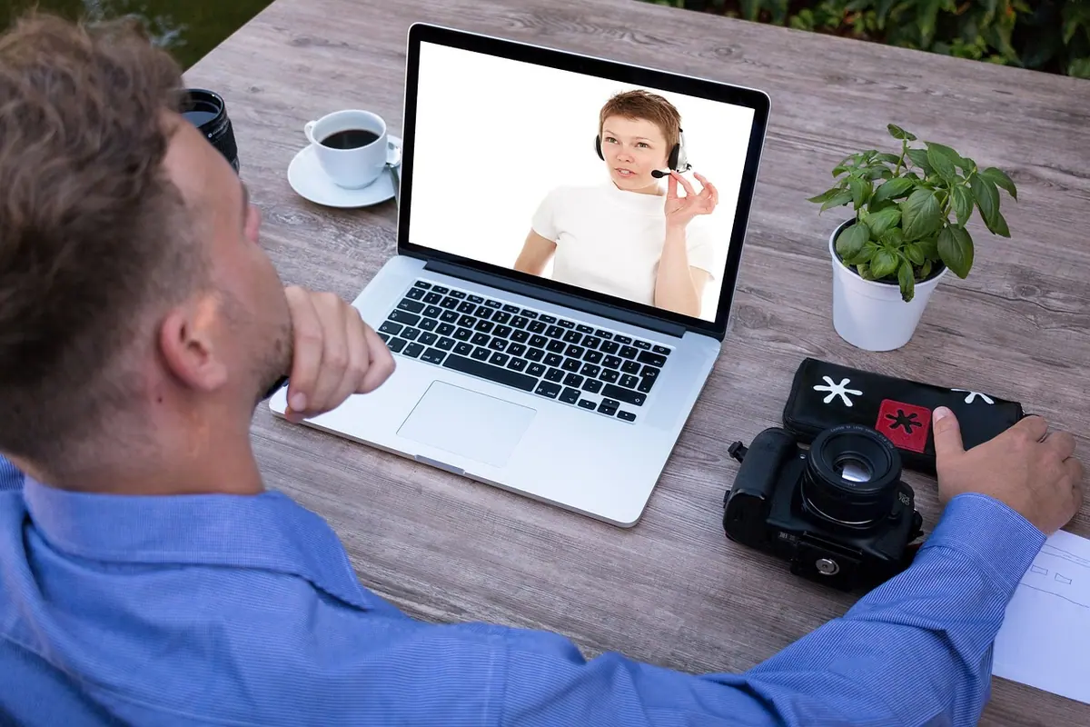 Bărbat la laptop, într-un apel video cu colegii, în timpul telemuncii